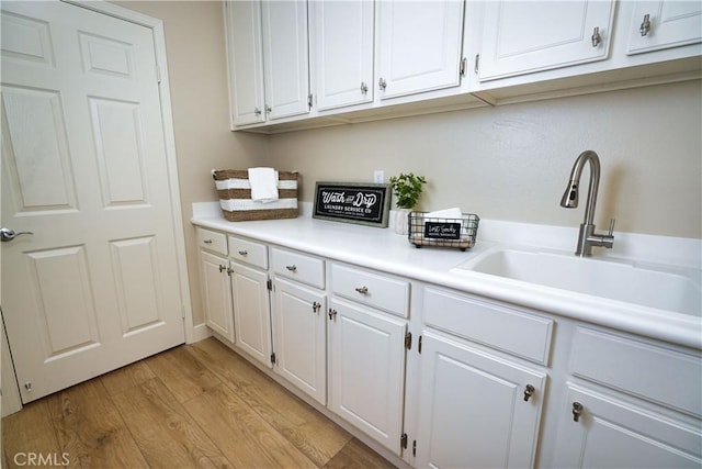 kitchen featuring white cabinetry, sink, and light hardwood / wood-style flooring