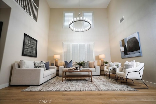 living room with a towering ceiling, wood-type flooring, and a chandelier