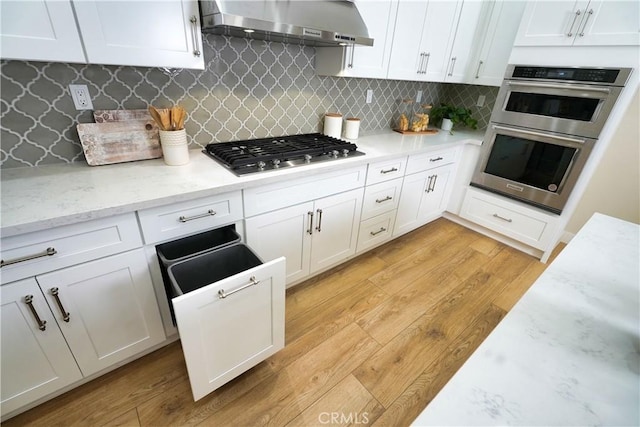 kitchen with white cabinetry, appliances with stainless steel finishes, and wall chimney range hood