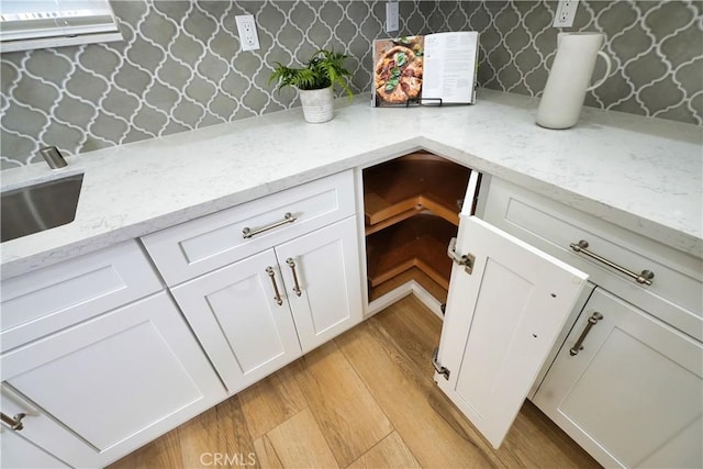 details featuring sink, light stone countertops, light hardwood / wood-style floors, and white cabinets