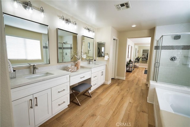 bathroom featuring wood-type flooring, shower with separate bathtub, and vanity