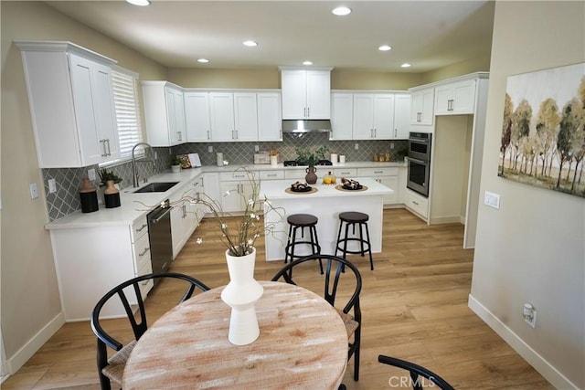 kitchen with sink, appliances with stainless steel finishes, white cabinets, and a kitchen island