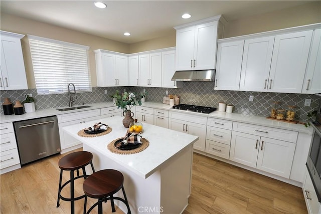 kitchen with a kitchen island, appliances with stainless steel finishes, sink, white cabinets, and a kitchen breakfast bar