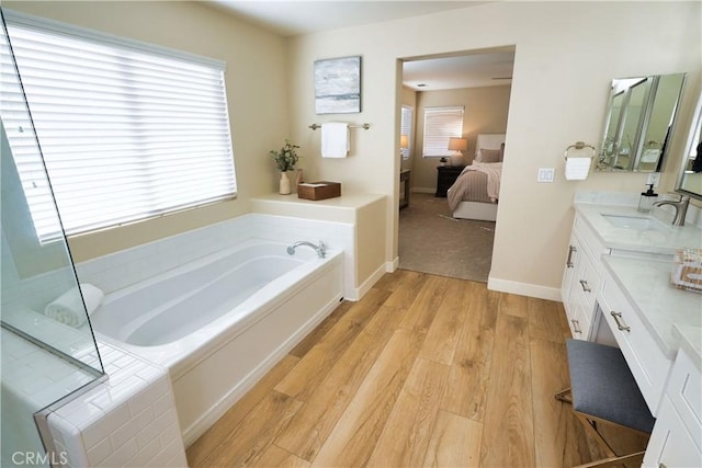 bathroom with vanity, hardwood / wood-style floors, and a relaxing tiled tub