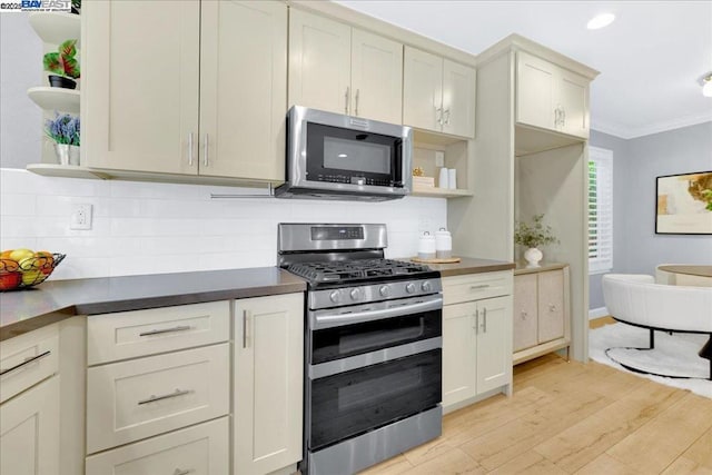 kitchen with crown molding, light wood-type flooring, appliances with stainless steel finishes, decorative backsplash, and cream cabinetry