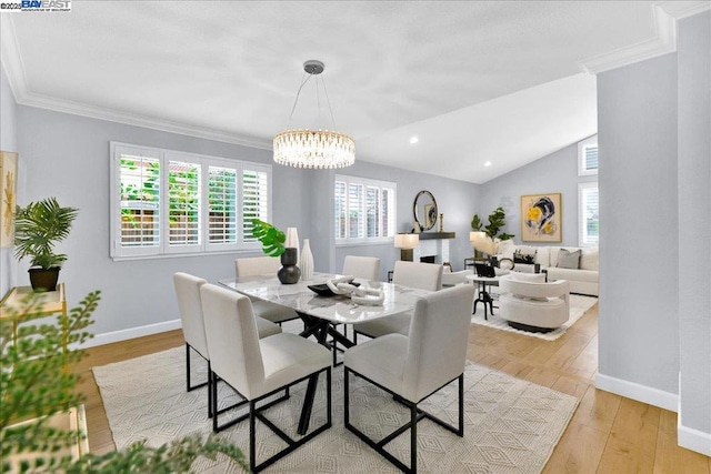 dining area featuring lofted ceiling, crown molding, light hardwood / wood-style floors, and an inviting chandelier