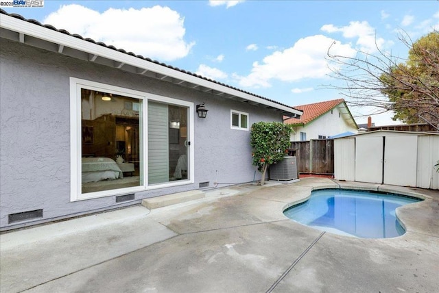 view of swimming pool featuring a patio area, central air condition unit, and a shed