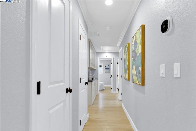 corridor with ornamental molding and light wood-type flooring