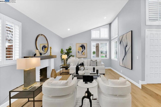 living room with a fireplace, high vaulted ceiling, and light hardwood / wood-style flooring