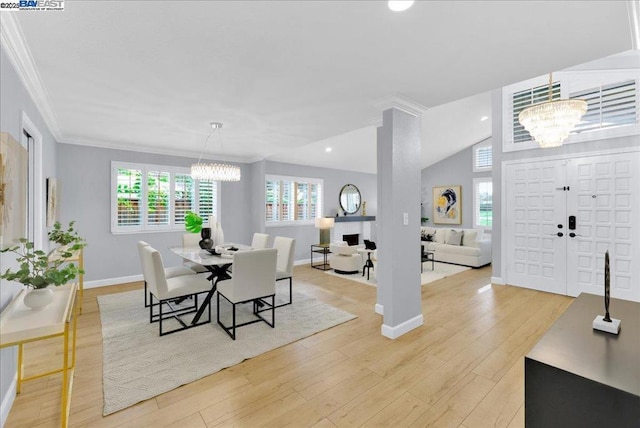 dining space with lofted ceiling, a notable chandelier, ornamental molding, and light hardwood / wood-style floors