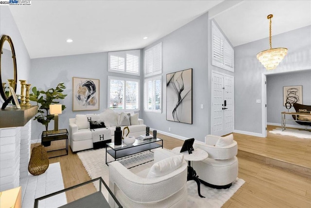 living room featuring high vaulted ceiling, a chandelier, and light wood-type flooring