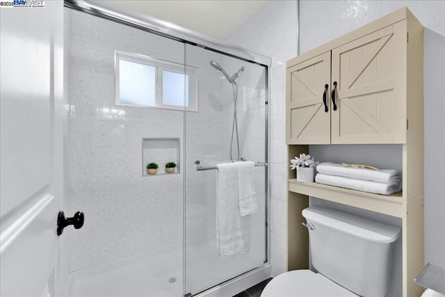 bathroom featuring a shower with shower door and toilet