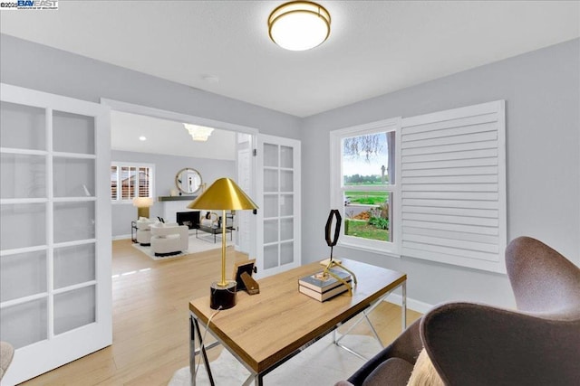 office area with light hardwood / wood-style floors and french doors