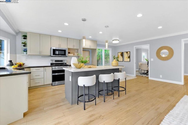 kitchen with decorative backsplash, hanging light fixtures, a center island, stainless steel appliances, and light hardwood / wood-style flooring