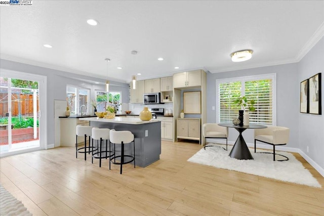 kitchen with crown molding, a healthy amount of sunlight, pendant lighting, and light wood-type flooring