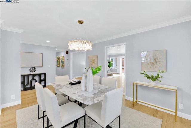 dining space with crown molding, an inviting chandelier, and light hardwood / wood-style floors