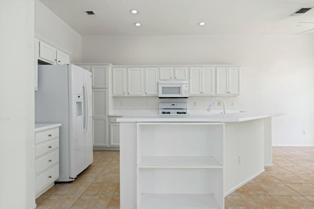 kitchen featuring a kitchen island with sink, light tile patterned floors, white cabinets, and white appliances