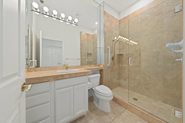 bathroom featuring toilet, vanity, tile patterned floors, and a shower with shower door