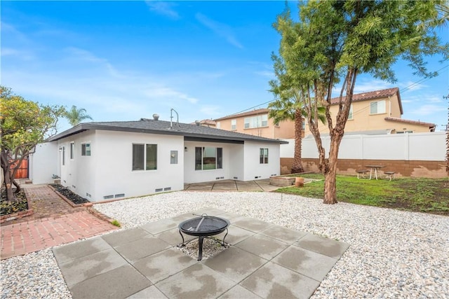 back of property with a patio, a fenced backyard, a fire pit, crawl space, and stucco siding