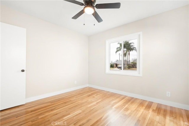 empty room featuring baseboards, ceiling fan, and light wood-style floors