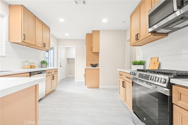 kitchen featuring stainless steel appliances, light brown cabinetry, and light countertops