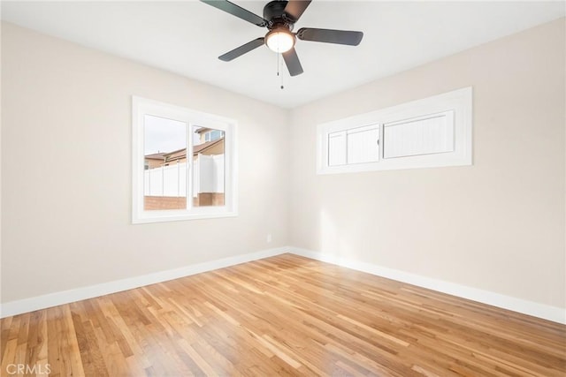 empty room featuring baseboards, wood finished floors, a ceiling fan, and a healthy amount of sunlight