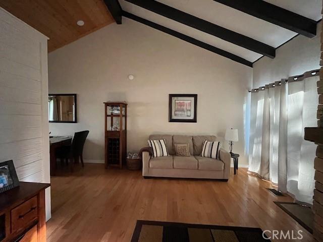 living room with beam ceiling, high vaulted ceiling, and light hardwood / wood-style flooring