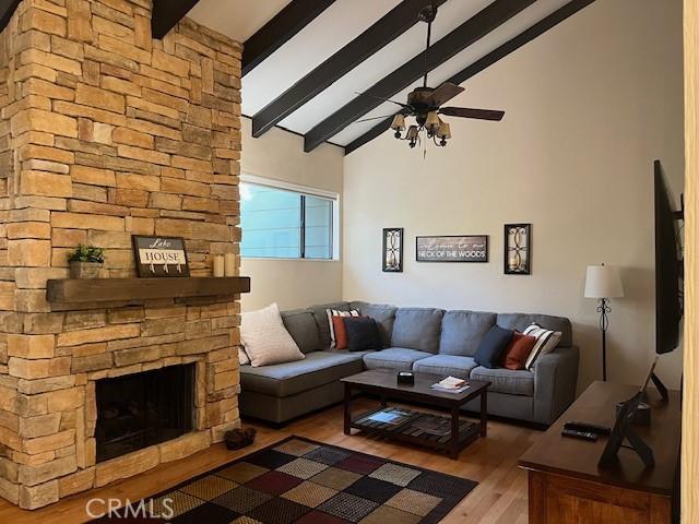 living room featuring hardwood / wood-style flooring, ceiling fan, beam ceiling, high vaulted ceiling, and a fireplace