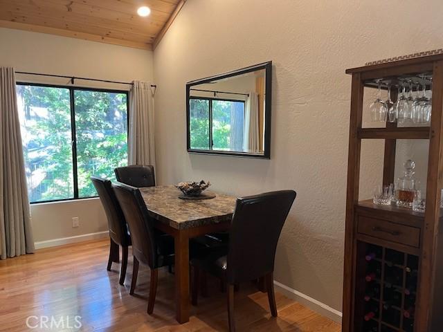 dining room with lofted ceiling, wooden ceiling, and light wood-type flooring