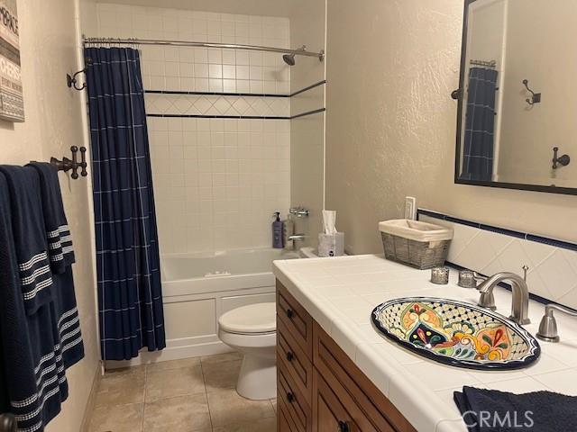 full bathroom with tile patterned flooring, vanity, shower / bath combination with curtain, and toilet