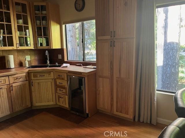 kitchen with tasteful backsplash, sink, light hardwood / wood-style floors, and light brown cabinetry