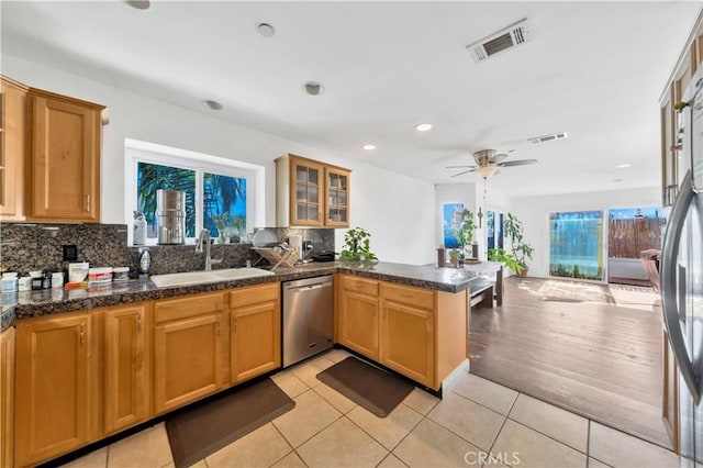 kitchen with sink, decorative backsplash, light tile patterned floors, kitchen peninsula, and stainless steel appliances