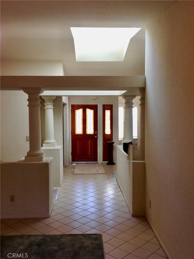 foyer featuring decorative columns and light tile patterned flooring