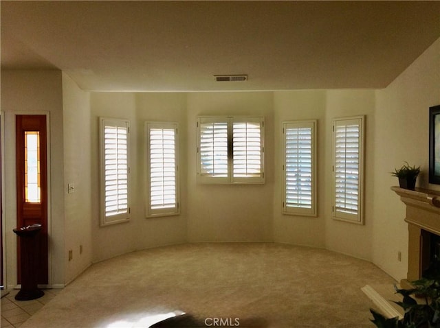 unfurnished living room featuring a healthy amount of sunlight and light carpet