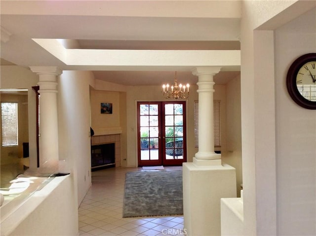 tiled foyer with ornate columns, a tiled fireplace, and french doors