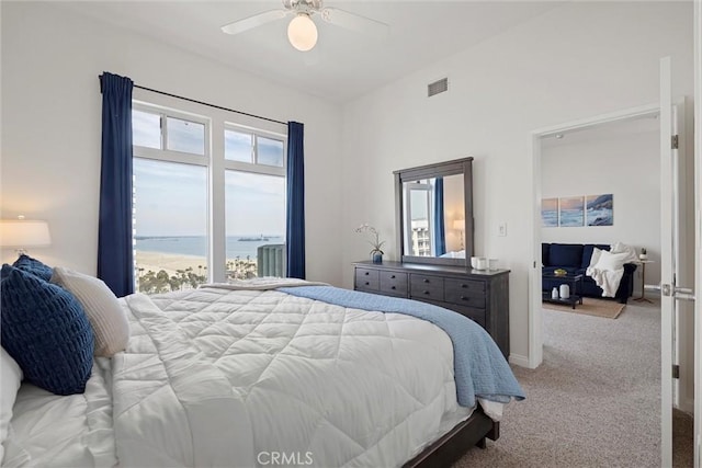 carpeted bedroom with a water view and ceiling fan