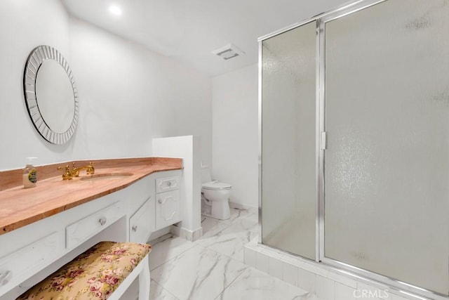 bathroom featuring vanity, a shower with door, and toilet