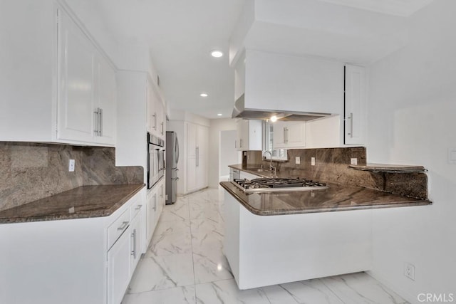 kitchen with sink, white cabinetry, dark stone countertops, appliances with stainless steel finishes, and kitchen peninsula