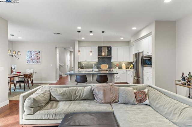 living room featuring wood-type flooring, sink, and a notable chandelier