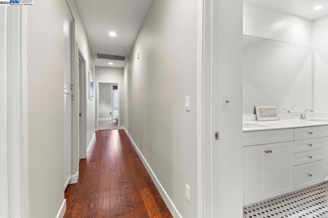 corridor with dark wood-type flooring and sink