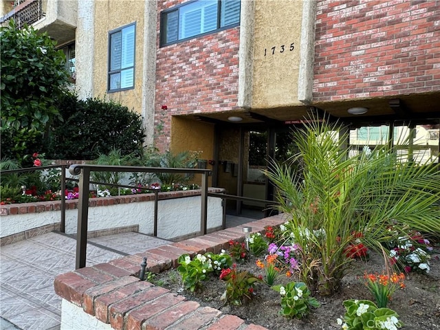 doorway to property with brick siding and stucco siding