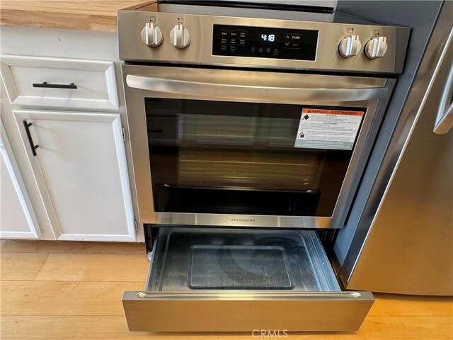 details featuring white cabinetry, double wall oven, and light wood-type flooring