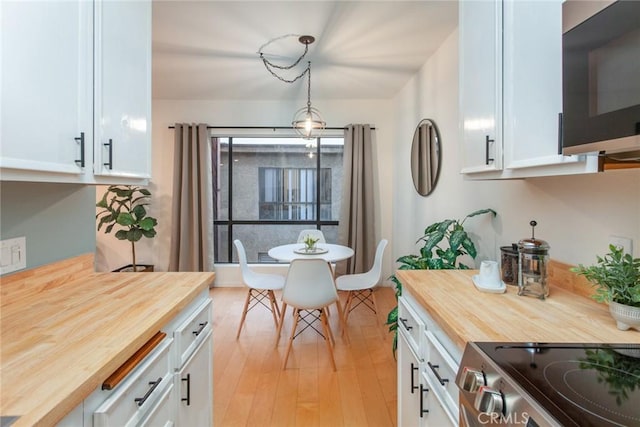 kitchen with light wood finished floors, butcher block countertops, white cabinets, and stainless steel range with electric cooktop