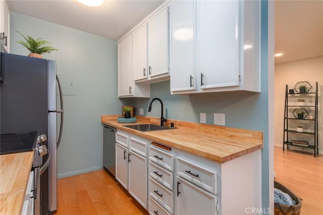 kitchen featuring white cabinetry, appliances with stainless steel finishes, sink, and butcher block countertops