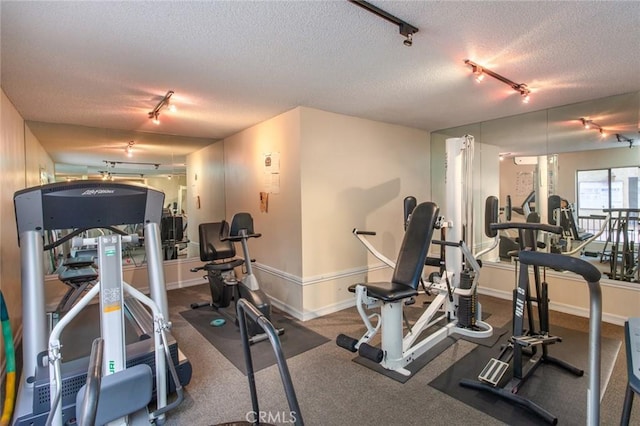 workout area with rail lighting, a textured ceiling, and baseboards