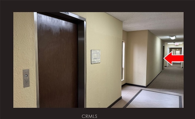 hallway with a textured ceiling and elevator