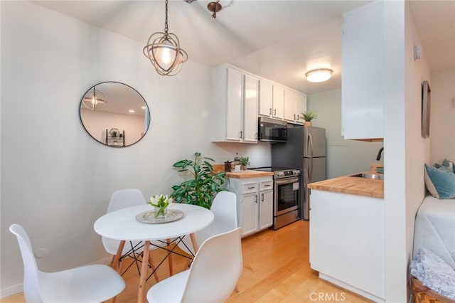 kitchen featuring electric range, butcher block countertops, a sink, white cabinetry, and light wood-style floors