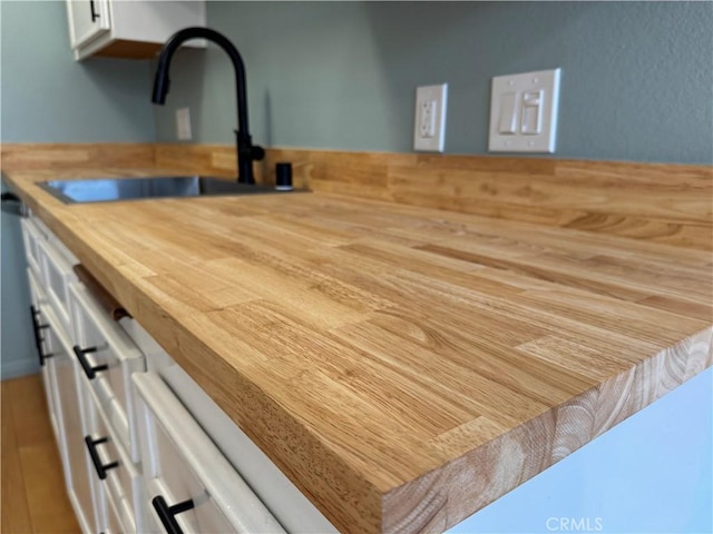 interior details featuring white cabinetry, butcher block counters, and a sink