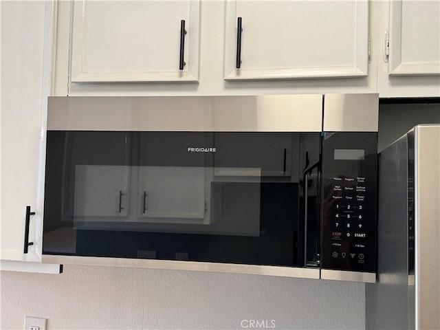 interior details featuring stainless steel microwave and white cabinetry