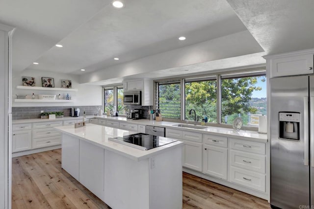 kitchen with a center island, tasteful backsplash, a sink, stainless steel appliances, and light countertops